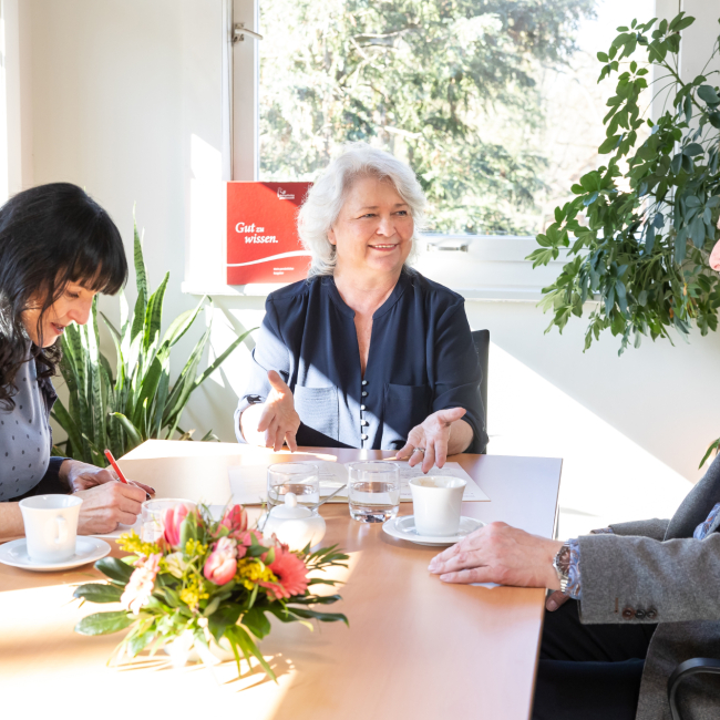 Freundeskreis: drei Menschen sitzen zusammen an einem Tisch