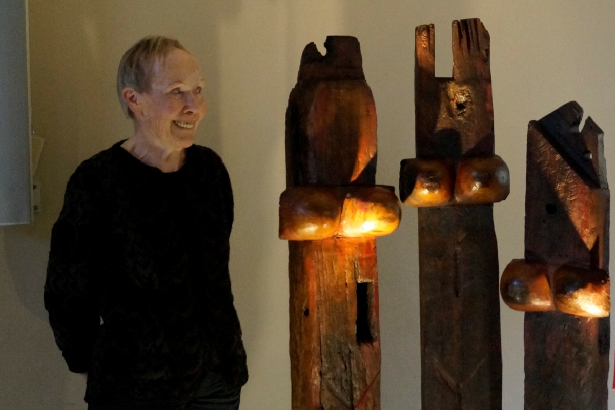 Ältere Frau neben hölzerner Skulptur