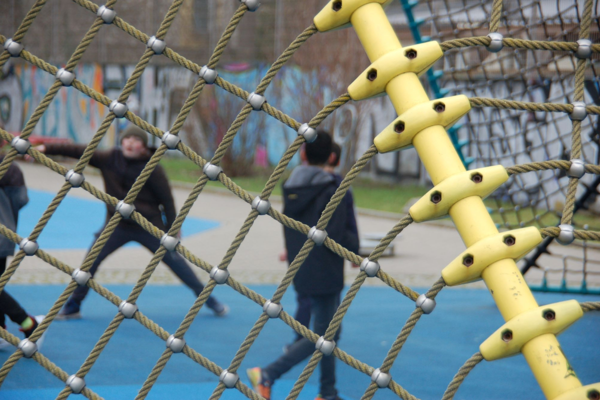 Spielende Kinder, im Vordergrund das Netz eines Fußballtores