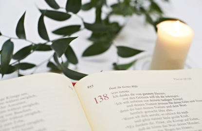 Detailansicht einer Bibelstelle mit einer Kerze im Hintergrund