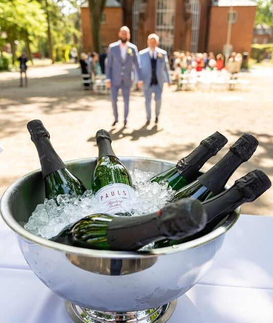 Sekt im Vordergrund und Hochzeitspaar im Hintergrund